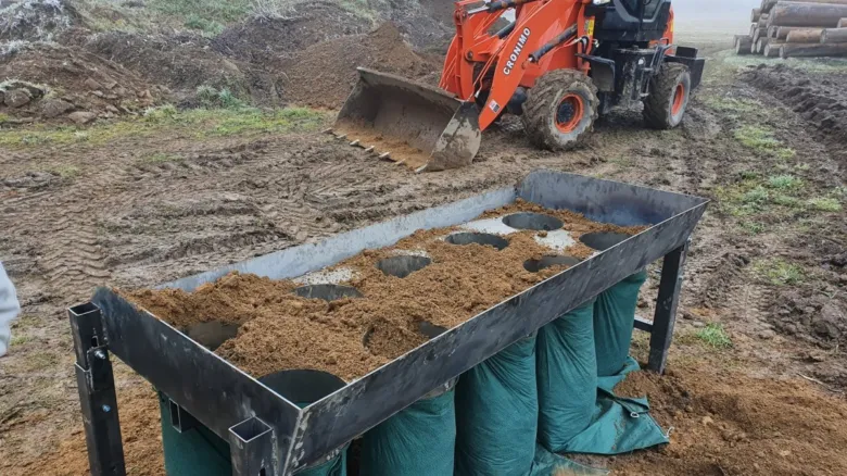 Stavební stroj upravuje svah pro terénní úpravu pozemku.