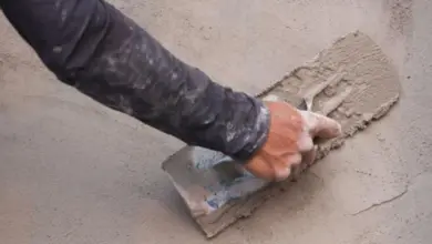 Ruka hladí čerstvý beton na venkovní povrchu.
