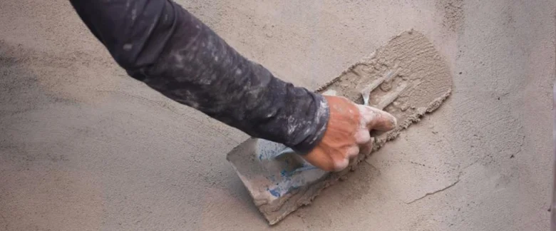 Ruka hladí čerstvý beton na venkovní povrchu.