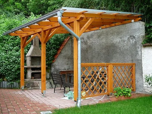 Dřevěná pergola s krytou střechou pro ochranu před větrem.