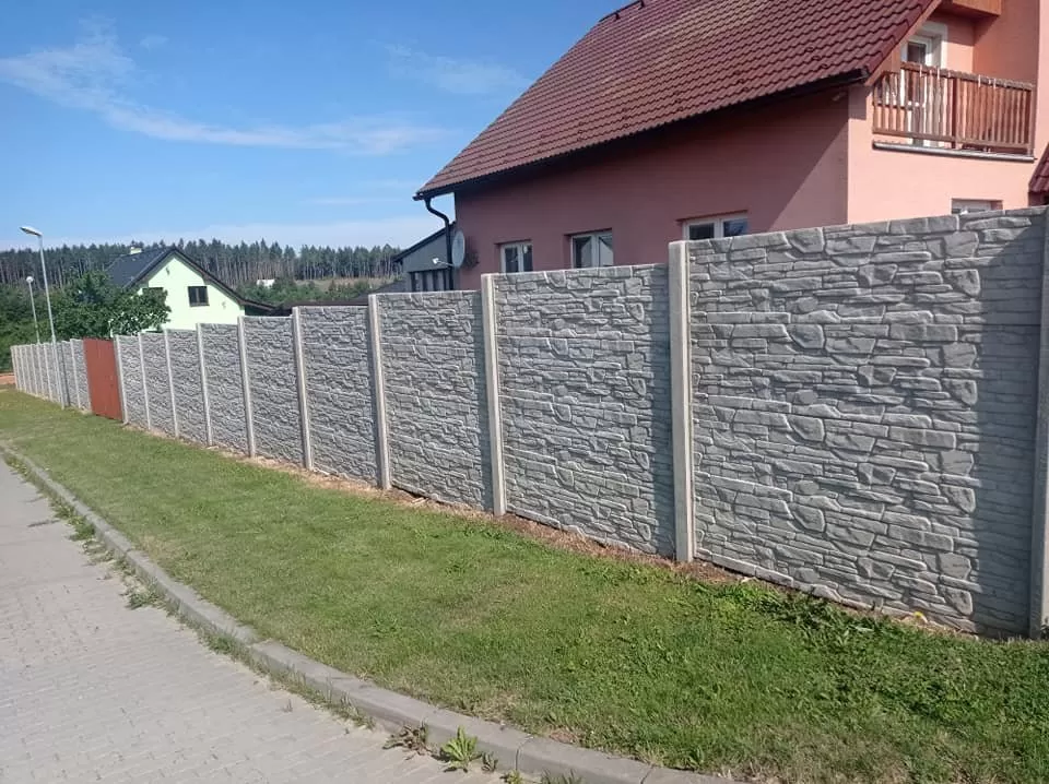 Betonový plot s kamennou úpravou na svahu u domu.