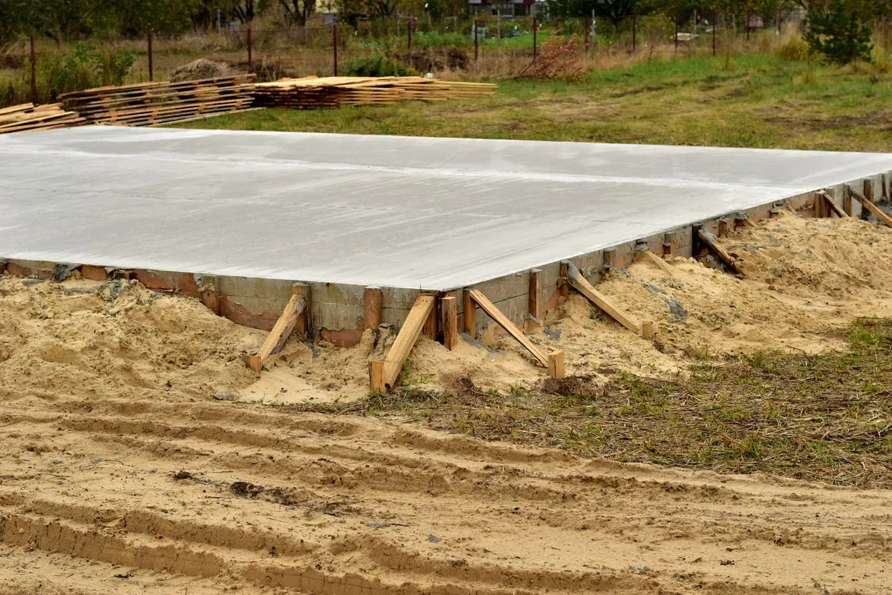 Nová betonová plovoucí základová deska s dřevěnými podpatky na staveništi.