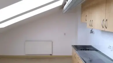 Prázdná kuchyň s nízkým šikmým stropem v podkroví.