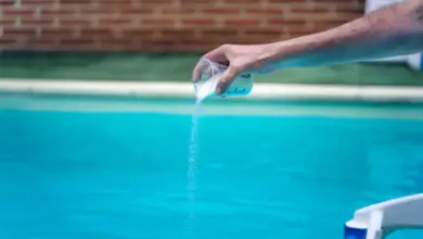 Lidé nalévají bílý prášek do bazénu měřicí šálkem.