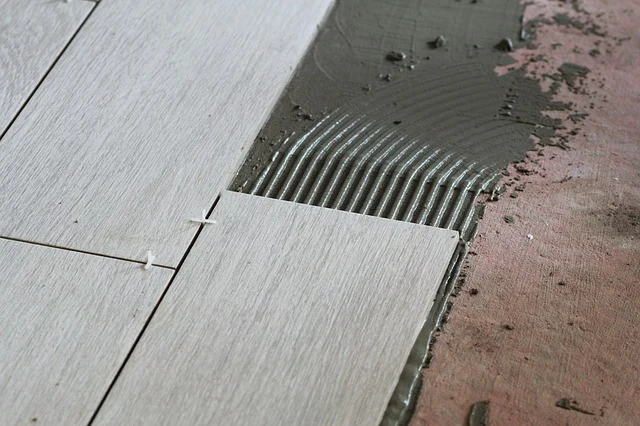 Krok při pokládce dlažby: lepidlo s hřebenem pod novou dlaždici.