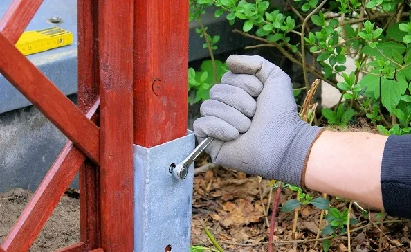 Ruční šroubení kovové podložky na dřevěný sloup.