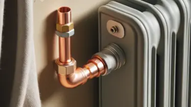 Měděný potrubí připojené k radiátoru topení na zdi.