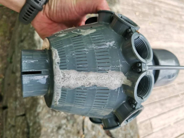 Ruční držení špinavého filtračního komponentu bazénu s pěnou.