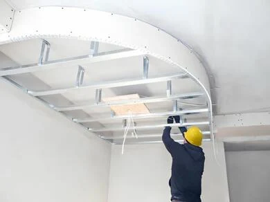 Stavebník montuje kovový rám pro sádrokartoný strop.