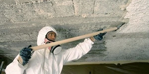 Pracovník v ochranném obleku likviduje azbestové stropní desky.