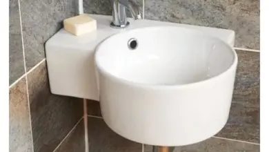 Bílá umyvadla na zeď v malém prostoru s šedými dlaždicemi.
