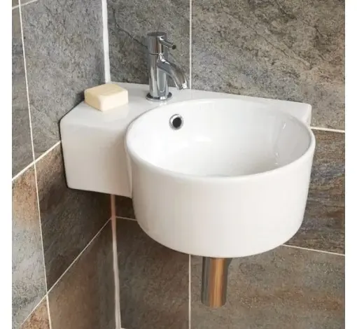 Bílá umyvadla na zeď v malém prostoru s šedými dlaždicemi.