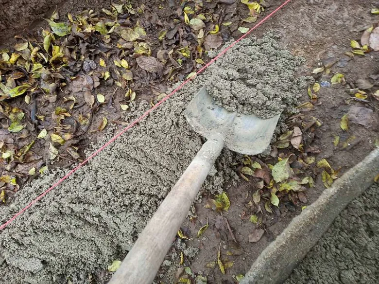 Lopata s čerstvým betonem pro stavbu obrubníku.