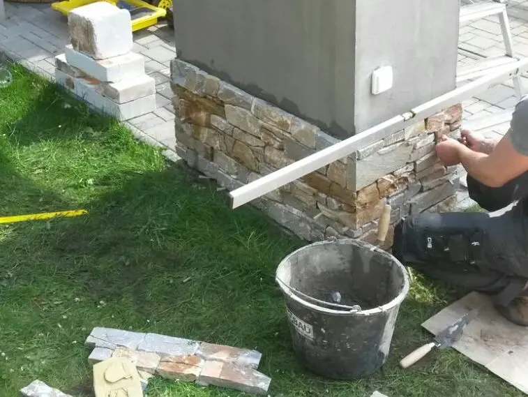 Montáž kamenného obkladu na roh budovy s použitím lepidla.
