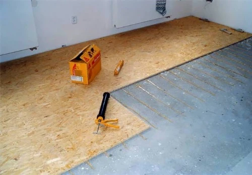 Instalace podlahy z desek OSB s lepidlem na betonovou základnu.