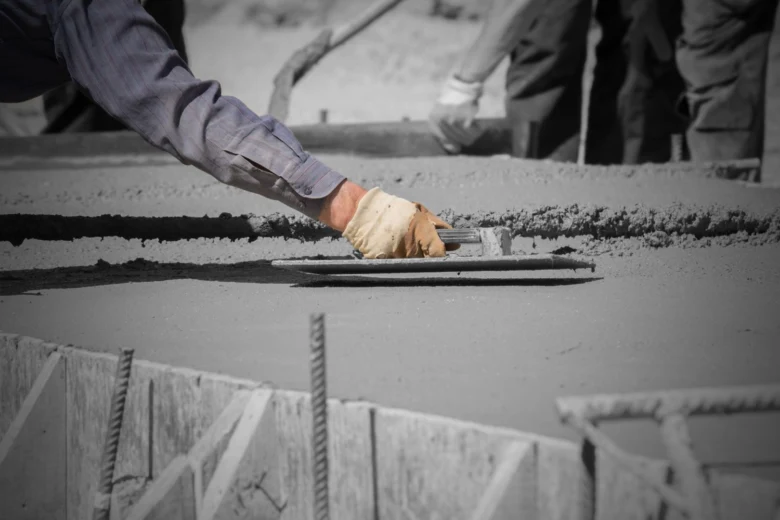 Stavebník vyrovnává čerstvý beton na základové desce.