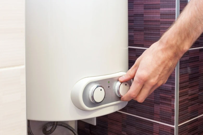 Ruka nastavuje teplotu na elektrokotle v koupelně.