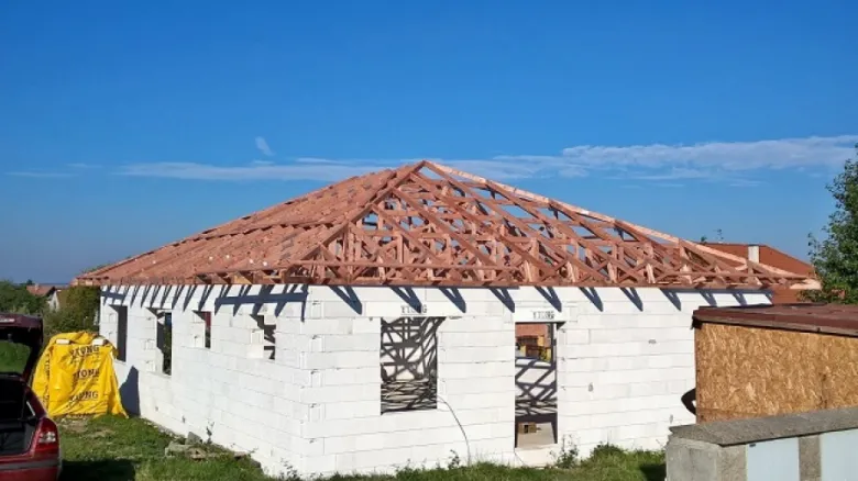 Stavba dřevěných příhradových vazníků na střeše domu.
