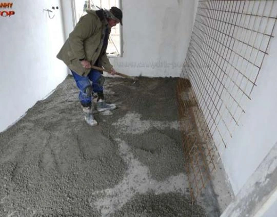 Stavebník nalévá betonovou podlahu s vloženou mřížkou pro topení.