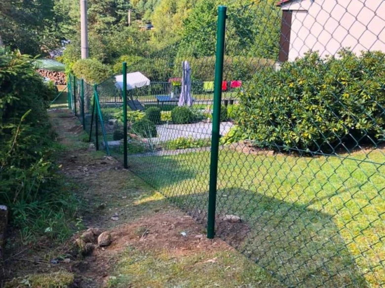 Zelený pletivový plot na svahu v zahradě
