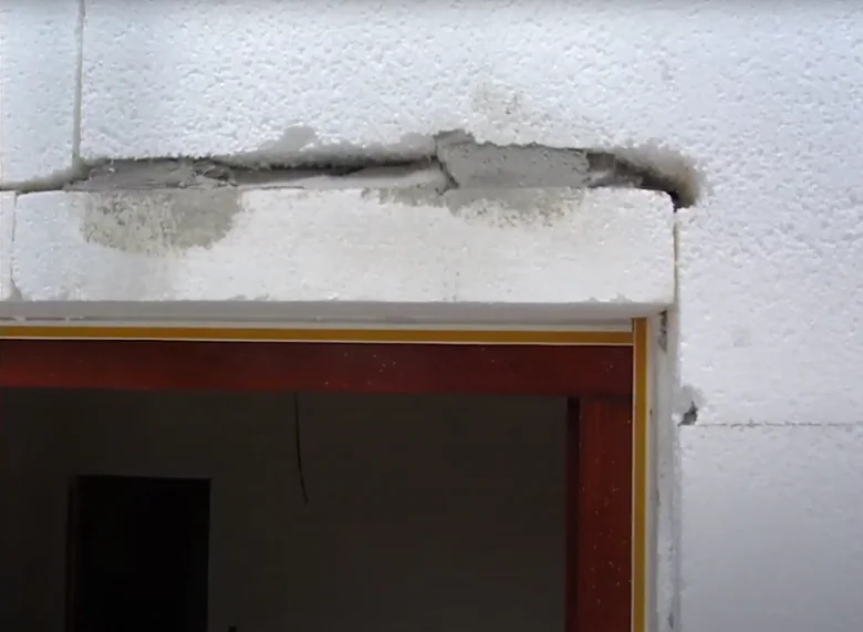 Poškozená těsnící hmota kolem rámu dveří v bloku z plynobetonu.