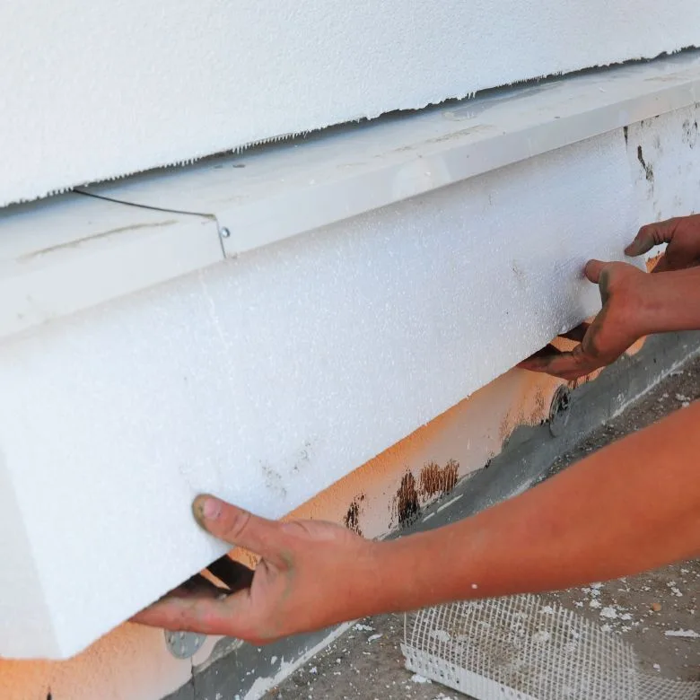 Ruční instalace tepelné izolace z polystyrenu na základ domu.