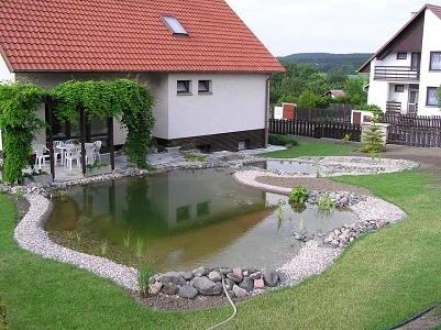 Koupací jezírko v zahradě s kameny a rostlinami.