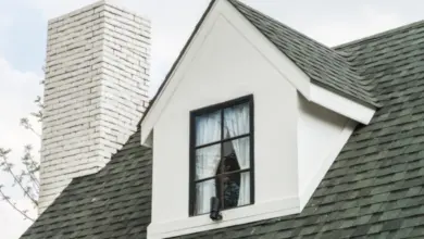 Bílý vikář na šindelové střechě s komínem.