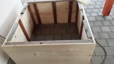 Částečně sestavený dřevěný kvetináč na dlažbě.