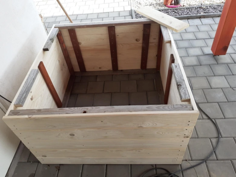 Částečně sestavený dřevěný kvetináč na dlažbě.