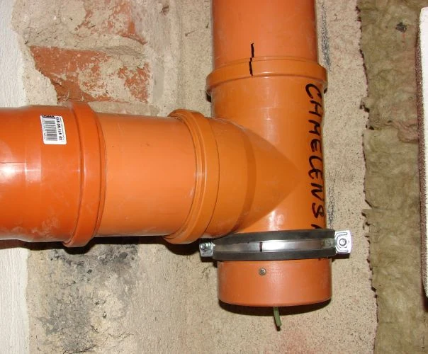 Oranžová plastová hadice pro odvod páry z digestoře.
