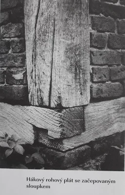 Detail dřevěného rohového spoje s kamennou zdí.
