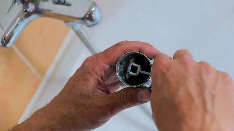 Ruce drží rozloženou baterii s viditelným vnitřním mechanismem.