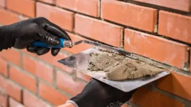 Stavebník nanáší maltu mezi cihly pomocí špachtle.
