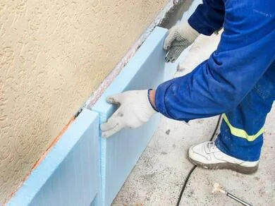 Montáž izolačních desek z expandovaného polystyrénu na stěnu.