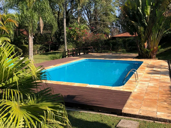Bazén s dřevěnou terasou a tropickou zahradní úpravou.