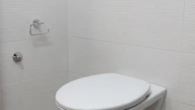 Bílý záchod na zeď v koupelně s bílými dlaždicemi.