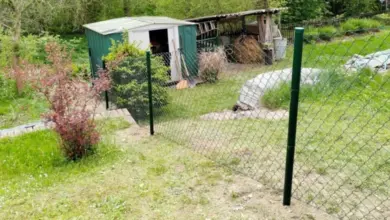 Plot na svahu s plotem, stodolou a zahradním pozemkem.