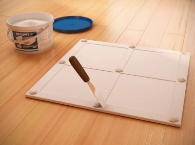 Příprava stropní kazety s lepidlem na podlaze pro instalaci.