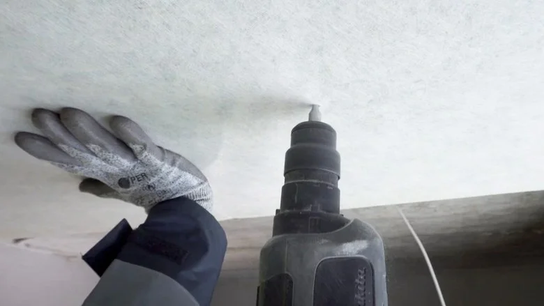 Ruční instalace tepelné izolace na strop zevnitř pomocí vrtáku.