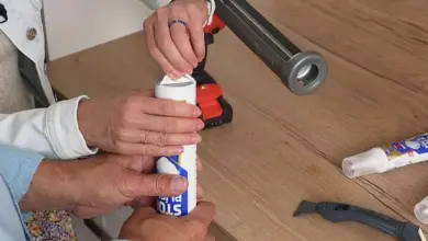 Ruční aplikace bílého silikonu z pistole na povrch.