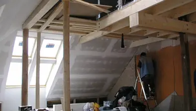 Stavební práce v podkroví během rekonstrukce s dřevěnými trámy.