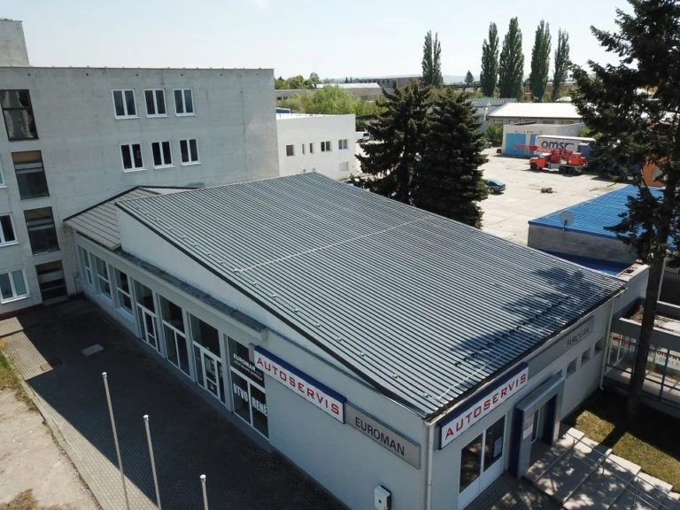 Pultová střecha z kovu na průmyslové budově s okny.