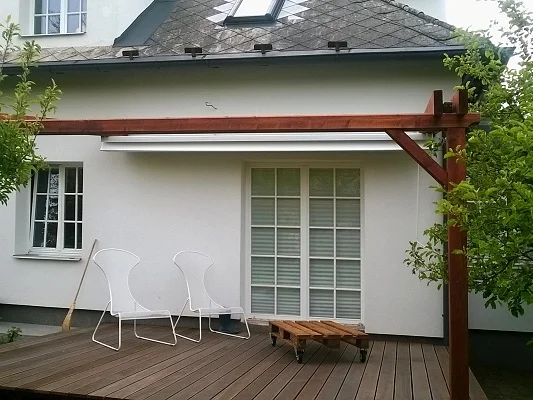 Dřevěná podlaha na terase altánu u bílého domu.