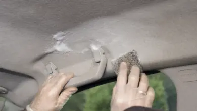 Ruční čištění čalounění stropu auta pěnou a houbou.