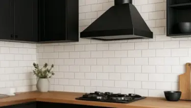 Černý odsávací digestoř s výfukovou trubicí v kuchyni.