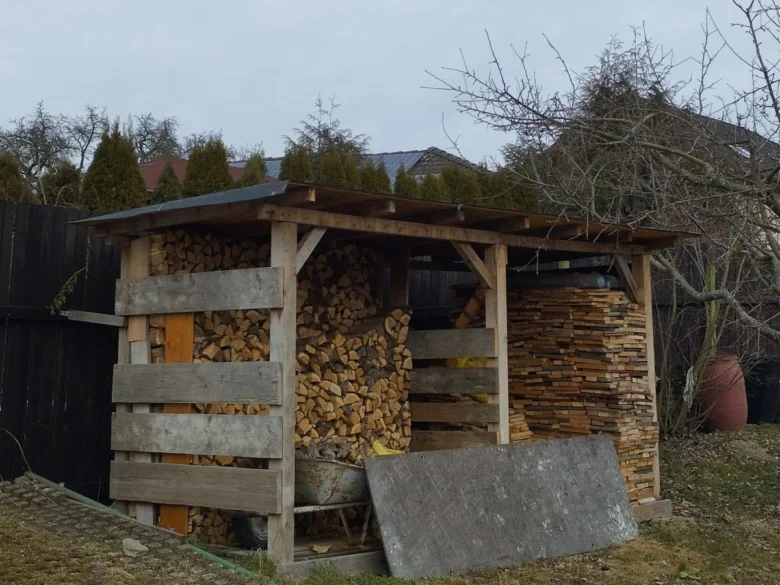 Dřevník postavený z palet plný dříví na zahradě.