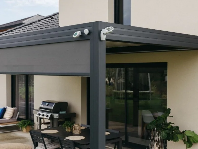 Modernní pergola s rolojící clonou pro zastínění venkovního prostoru.