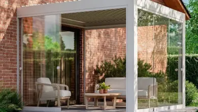 Skleněná designová pergola s pohovkou u cihlového domu.