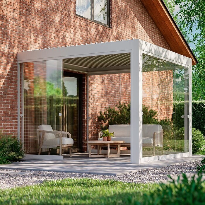 Skleněná designová pergola s pohovkou u cihlového domu.